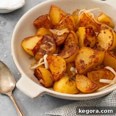 Close-up of crispy blackstone potatoes and onions in a white bowl, showcasing their golden-brown texture.