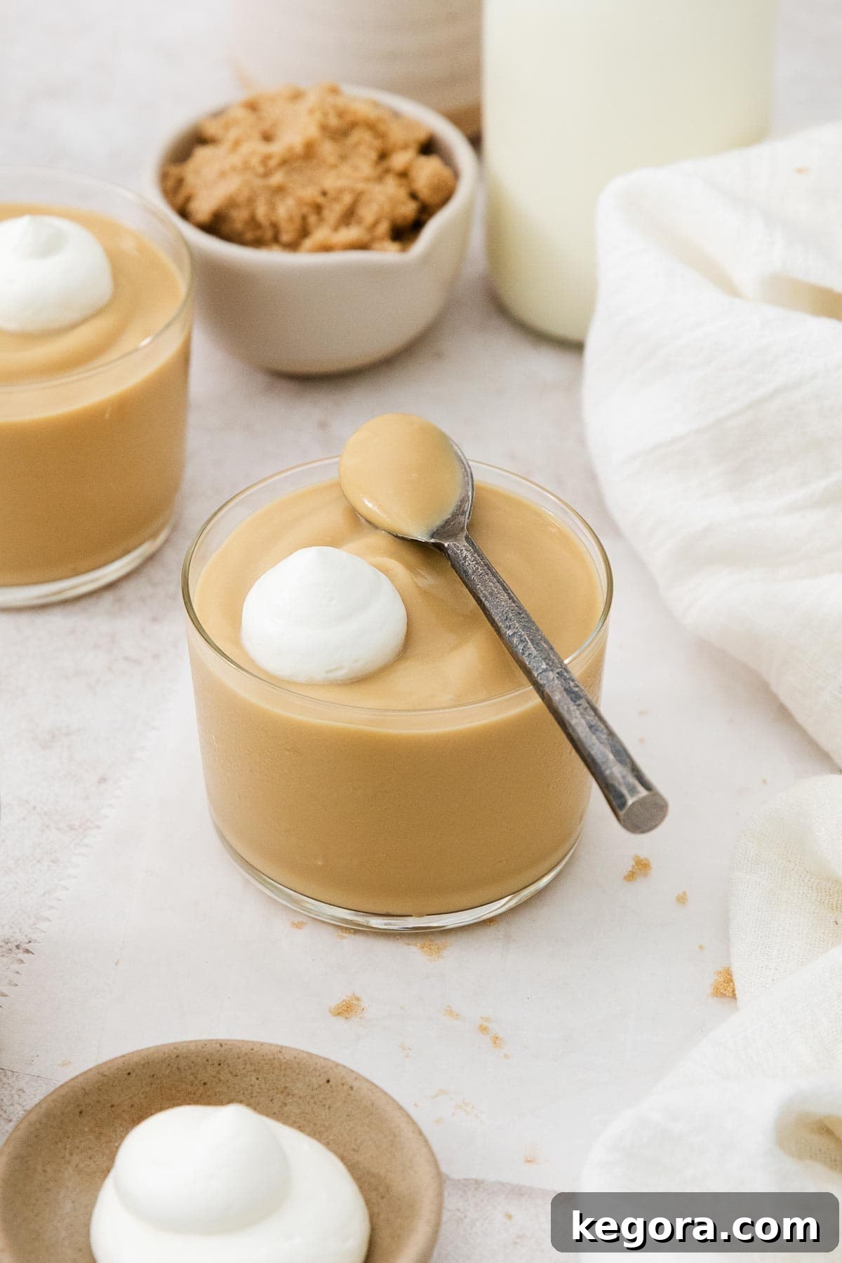 The Finest Butterscotch Pudding 3 Butterscotch pudding in a glass dish with a spoonful of pudding over the top, ready to be enjoyed.