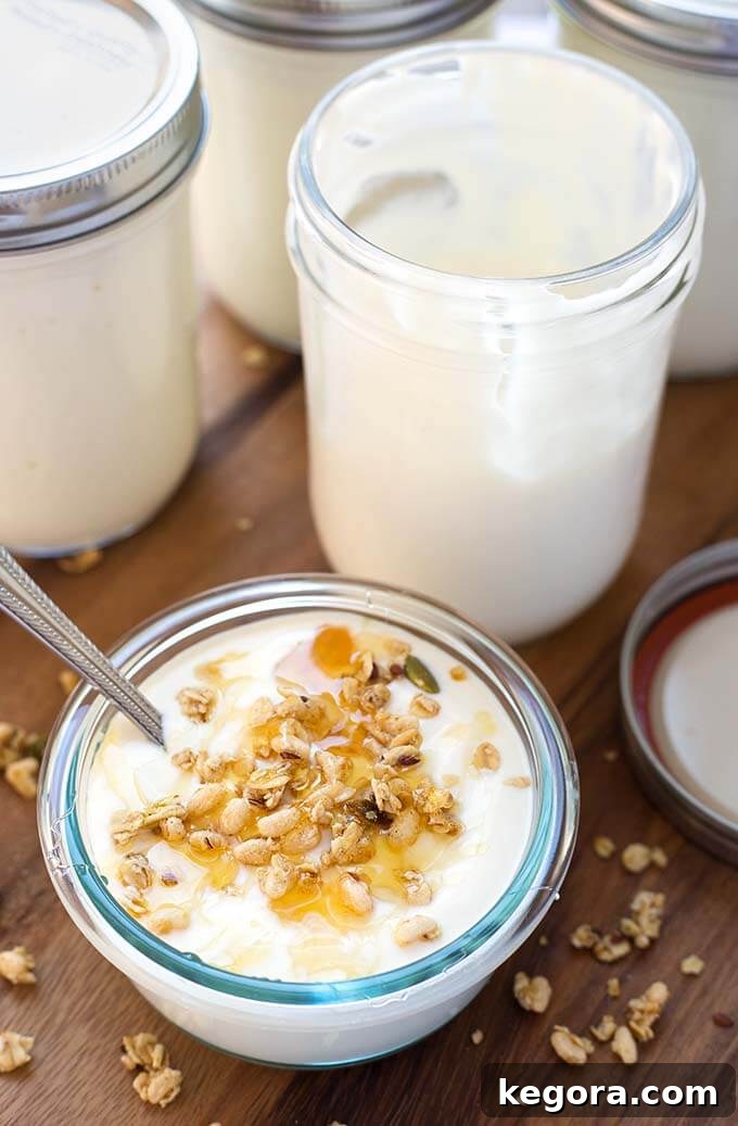 Effortless Instant Pot Yogurt 2 Small glass bowl of yogurt next to glass jars with yogurt, showcasing the creamy texture.