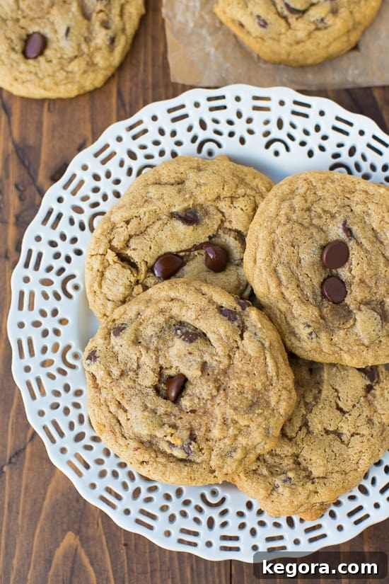 Wholesome Buckwheat Chocolate Chip Delights 2 Delicious buckwheat chocolate chip cookies arranged elegantly on a white plate, set against a rustic wooden background, highlighting their rich texture and golden-brown edges.