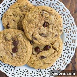 Golden-brown buckwheat cookies featuring delightful chocolate chips, artfully presented on a pristine white plate against a soft, rustic wooden background.