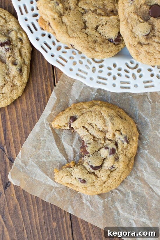 Wholesome Buckwheat Chocolate Chip Delights 3 A perfectly baked buckwheat chocolate chip cookie with a bite taken out, resting on a sheet of brown parchment paper, revealing its soft, chewy interior.