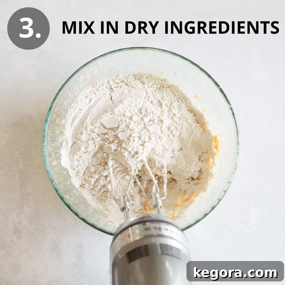 Wholesome Buckwheat Chocolate Chip Delights 7 The previously prepared dry ingredients being gently mixed into the wet batter in a glass bowl, ensuring a uniform and cohesive cookie dough.