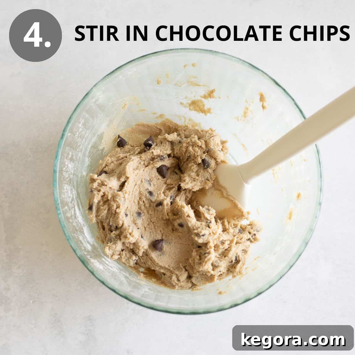 Wholesome Buckwheat Chocolate Chip Delights 8 A spatula gently folding chocolate chips into the rich, nutty buckwheat cookie dough within a glass mixing bowl, ensuring even distribution.