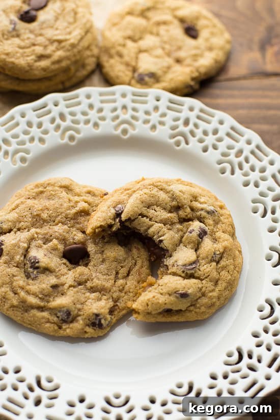 Buckwheat Chocolate Chip Cookies Two buckwheat chocolate chip cookies resting on a white plate, one with a bite taken out to reveal its soft, chocolatey interior, all set to be enjoyed.