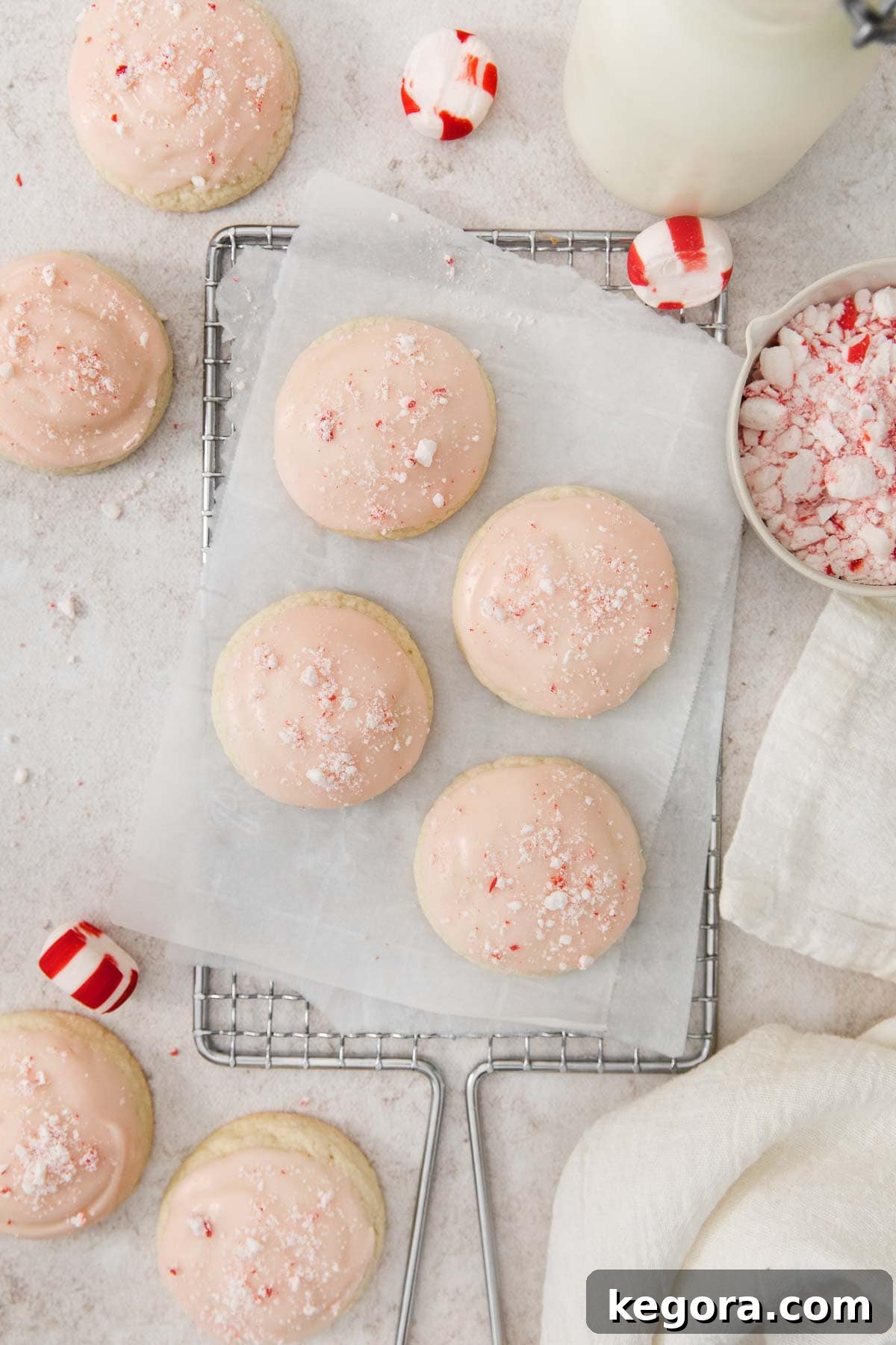 Velvet Gluten-Free Peppermint Melts 3 Peppermint meltaways topped with pink glaze and crushed peppermint candies, arranged neatly on a parchment-lined wire rack.