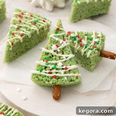 Beautifully decorated Christmas tree crispy treats arranged on a pristine white platter, ready for holiday festivities.