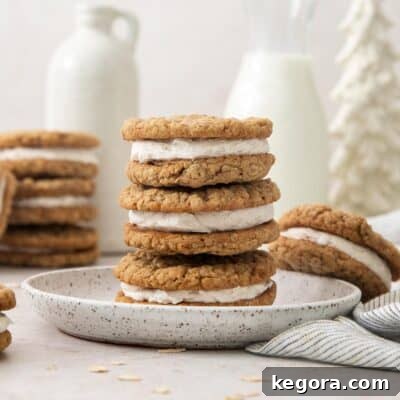 Eggnog oatmeal cream pies stacked appealingly on a plate, with more in the blurred background, ready to be enjoyed.
