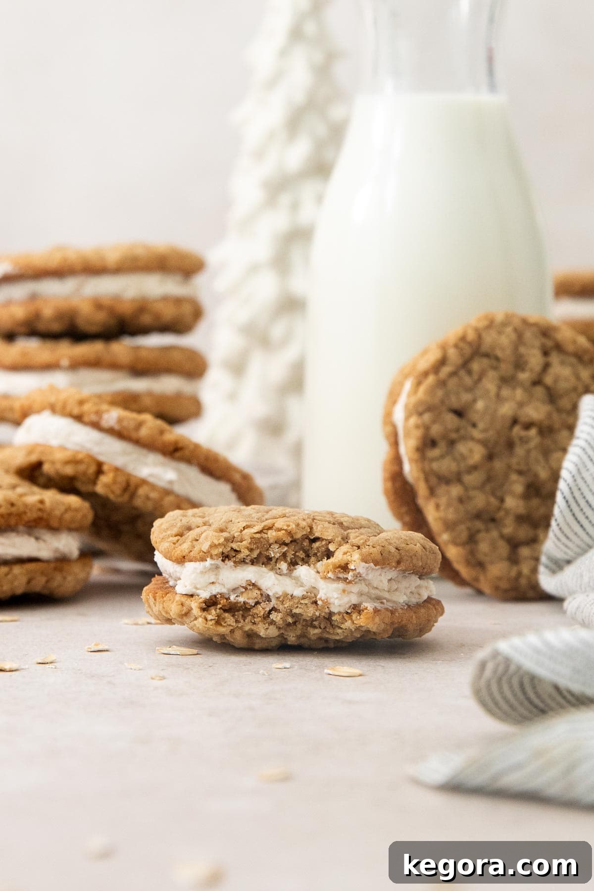 An eggnog oatmeal cream pie with a bite missing, showcasing the creamy filling and soft cookie, with more cookies in the background.