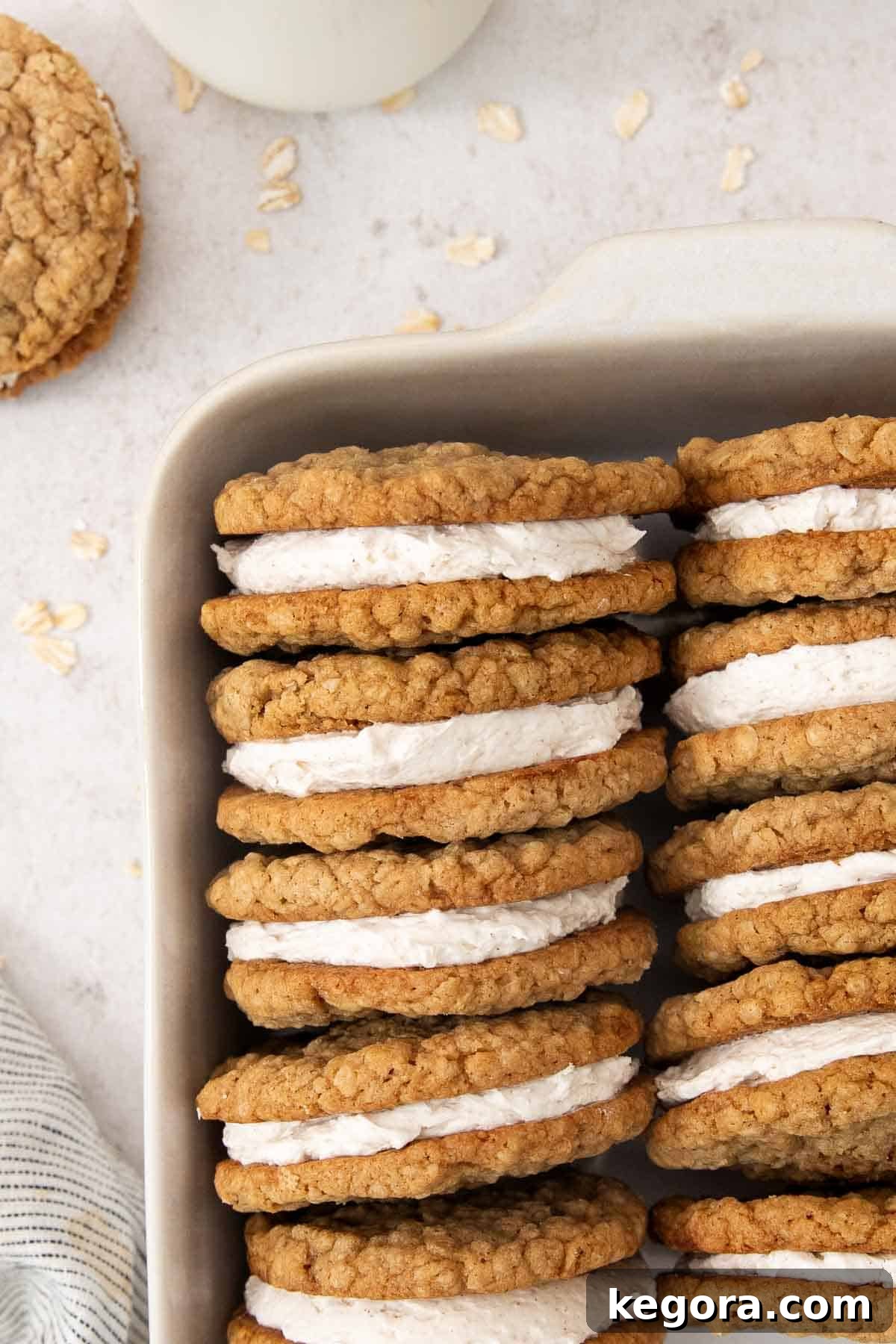 Rows of fully assembled eggnog oatmeal cream pies, neatly arranged on their sides in a baking dish.