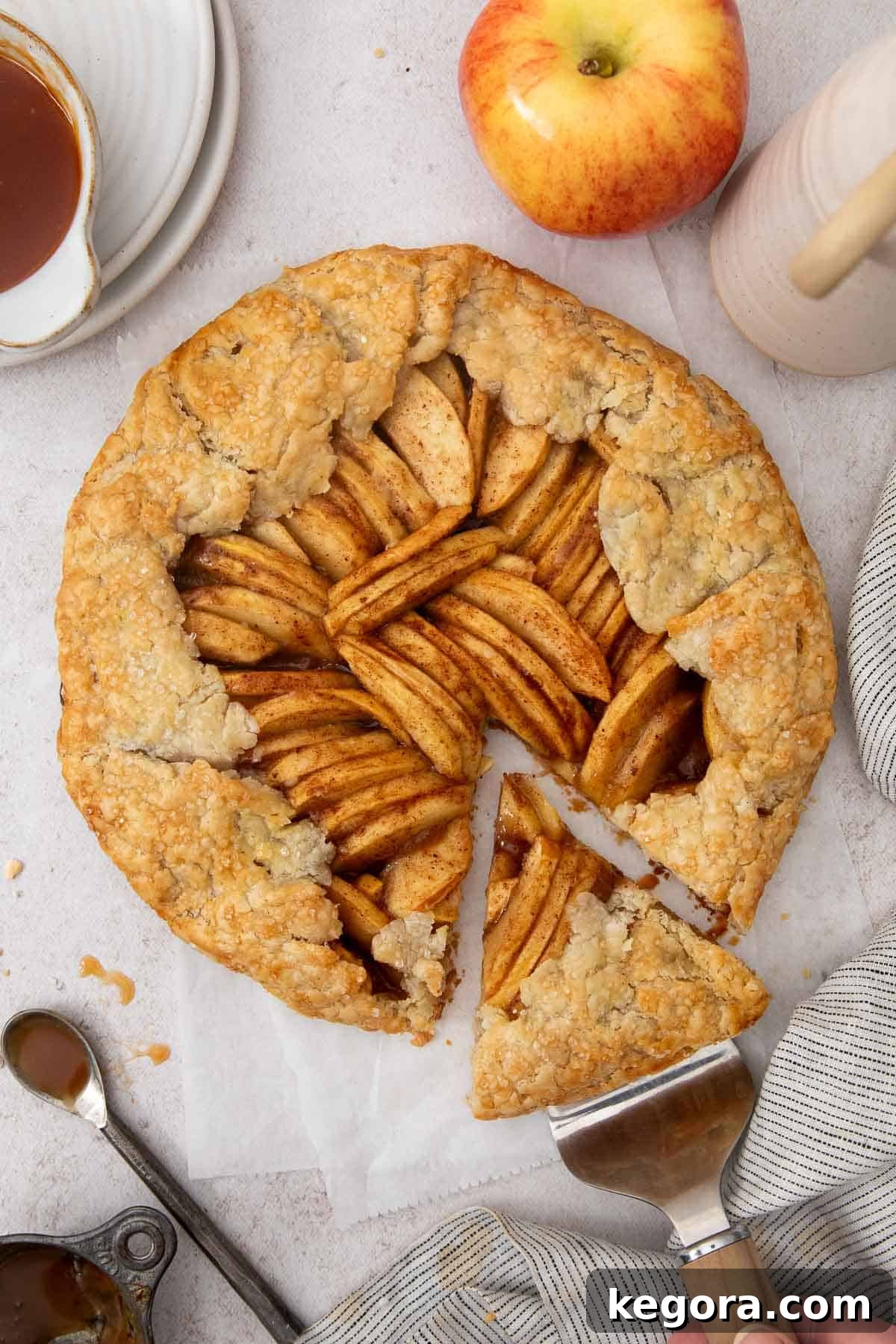 Flaky Gluten-Free Apple Galette 3 A delectable slice of gluten-free apple galette being lifted from the whole dessert with a pie server, showcasing its golden crust and juicy apple filling.
