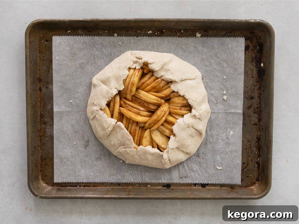 Flaky Gluten-Free Apple Galette 6 The apple galette assembly in progress, showing the edges of the dough gently folded over the apple filling, ready for egg wash and baking.