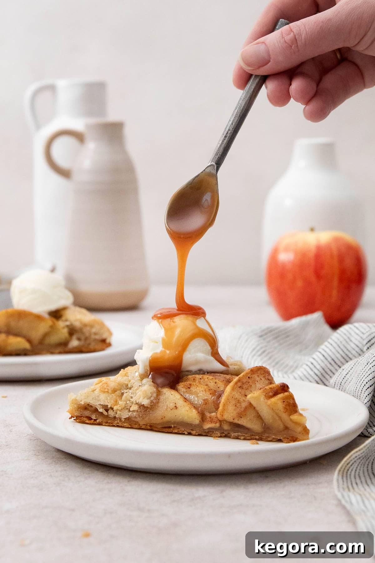 Flaky Gluten-Free Apple Galette 7 A close-up shot of rich salted caramel sauce being gracefully spooned over a warm slice of apple galette, which is topped with a scoop of vanilla ice cream, creating a luscious dessert.