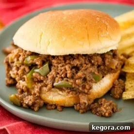 Sloppy Joes on a hamburger bun next to chips all on a blue plate.