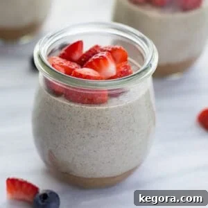 chia pudding in glass jar topped with berries on marble background