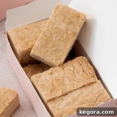 Perfectly baked gluten-free shortbread bars arranged in a charming gift box, with one piece propped up to showcase its golden perfection.