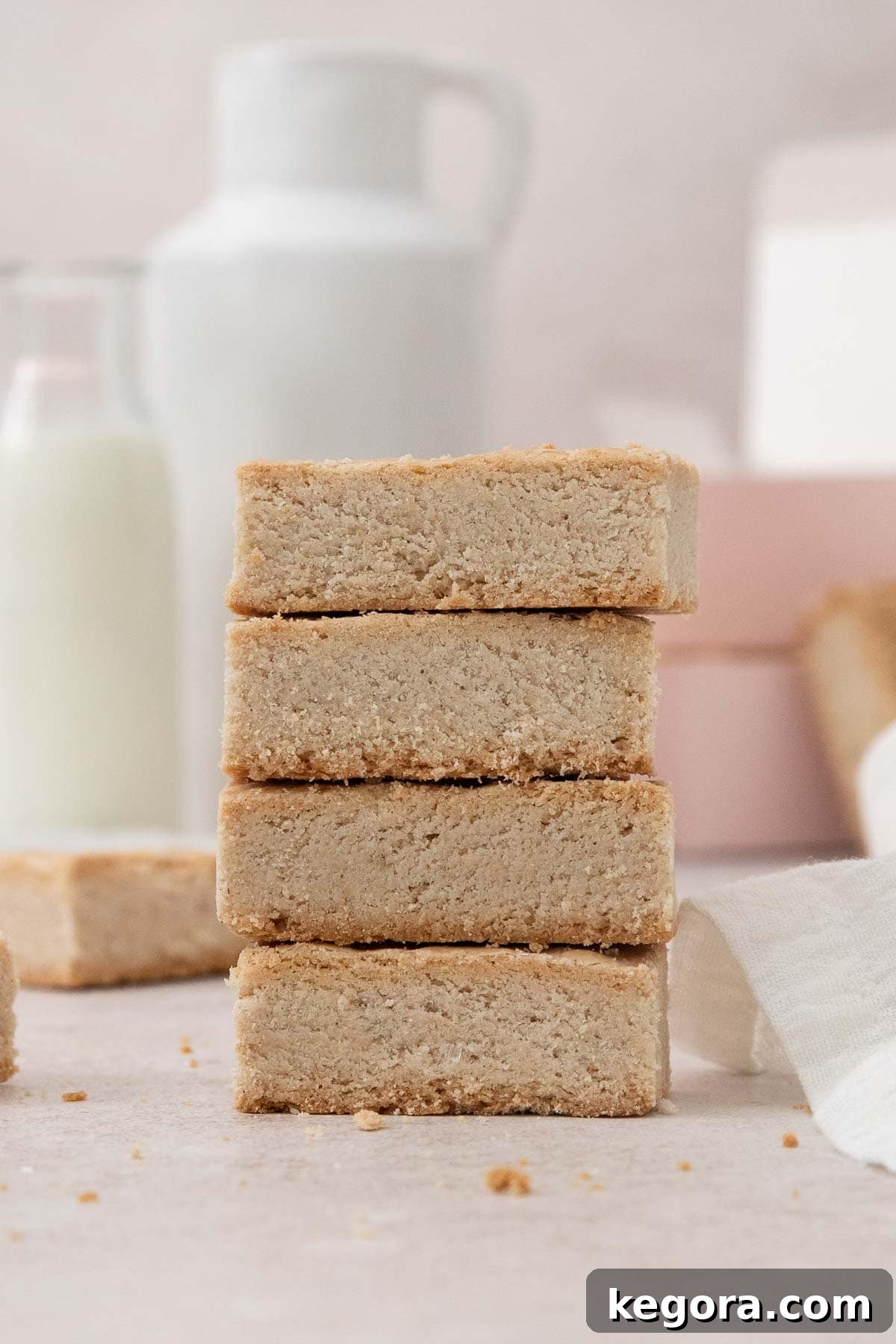Delicate slices of golden-brown gluten-free shortbread stacked artfully in a tower on a rustic wooden countertop, ready to be enjoyed.