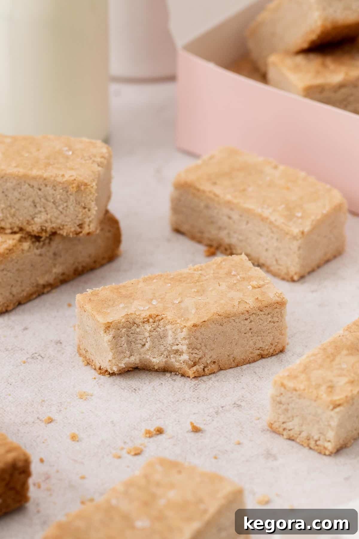 Golden brown gluten-free shortbread slices arranged elegantly on a rustic wooden board, with one cookie having a bite taken out, highlighting its delicious, tender texture.
