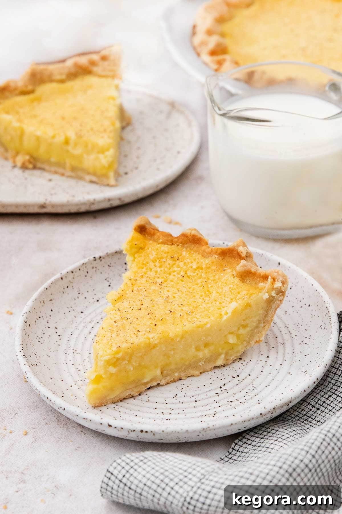 Southern Charm Gluten-Free Buttermilk Pie 6 A perfectly sliced piece of gluten-free buttermilk pie on a white plate, with a glass of milk in the background, ready to be enjoyed.