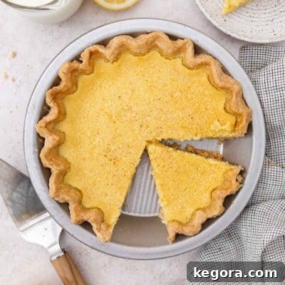 buttermilk pie in metal pie plate with slice taken out, showing the creamy filling and flaky crust