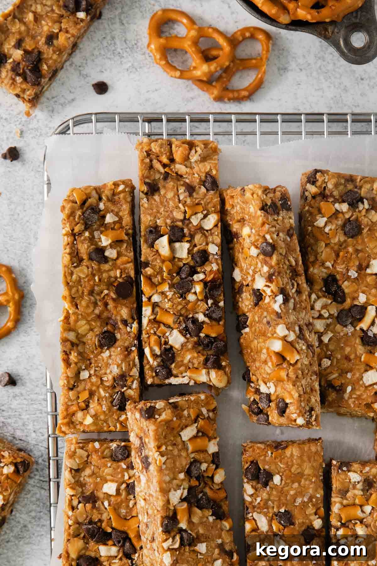 No-bake peanut butter oatmeal bars on a wire cooling rack with parchment paper, showcasing golden brown texture and sprinkled pretzel bits.