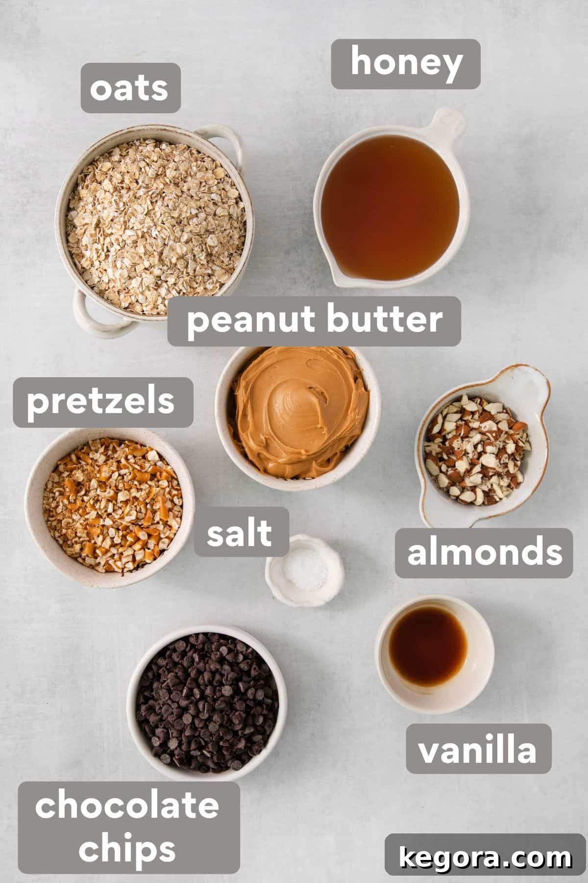 Collection of ingredients for no-bake peanut butter oatmeal bars laid out on a kitchen counter, including oats, pretzels, honey, and peanut butter.