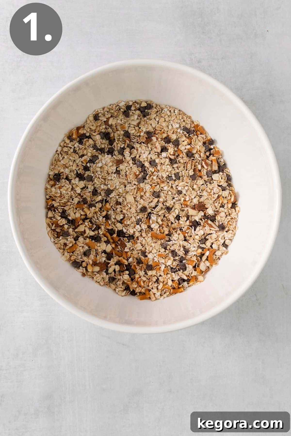 Crushed pretzels, oats, almonds, and chocolate chips in a mixing bowl.