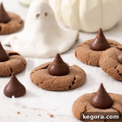 A cropped photo of festive gluten-free Nutella witch hat cookies, adorned with chocolate kisses, arranged on a wire cooling rack.