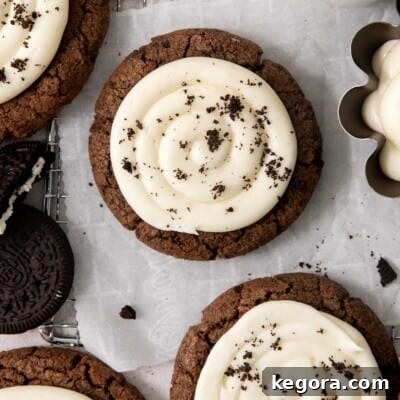 Gluten-free Oreo Crumbl cookies, generously frosted and topped with cookie pieces, resting on a wire rack with parchment paper.