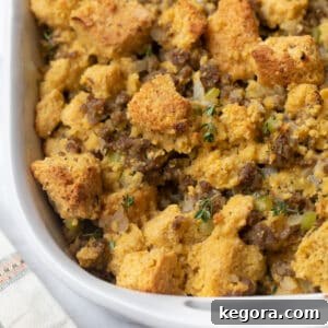 Silver spoon scooping sausage stuffing out of white casserole dish