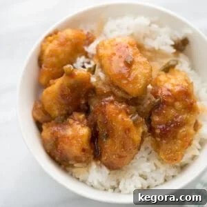 sticky chicken over rice in white bowl