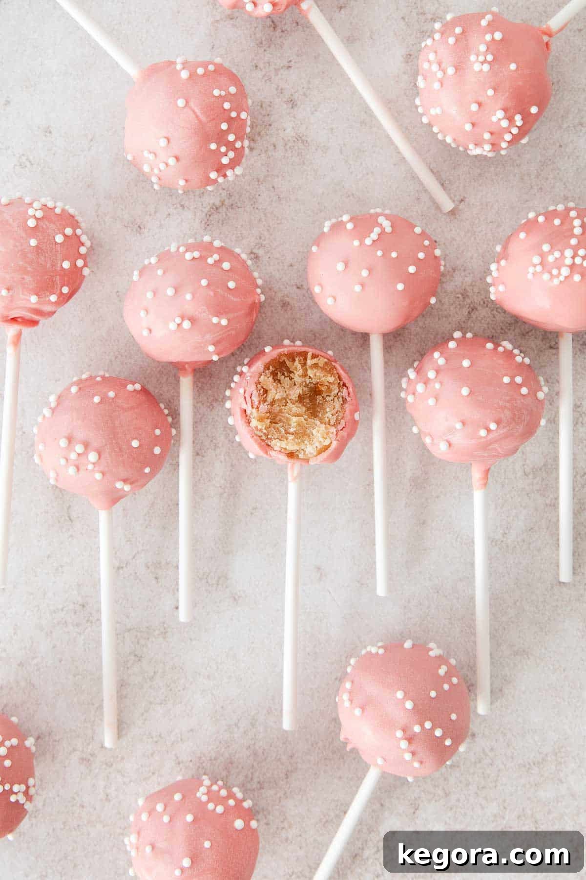 Guilt-Free Cake Pop Delights 3 A beautifully arranged line of gluten-free cake pops on a pristine countertop, with one pop showcasing a delightful bite, revealing its moist interior.