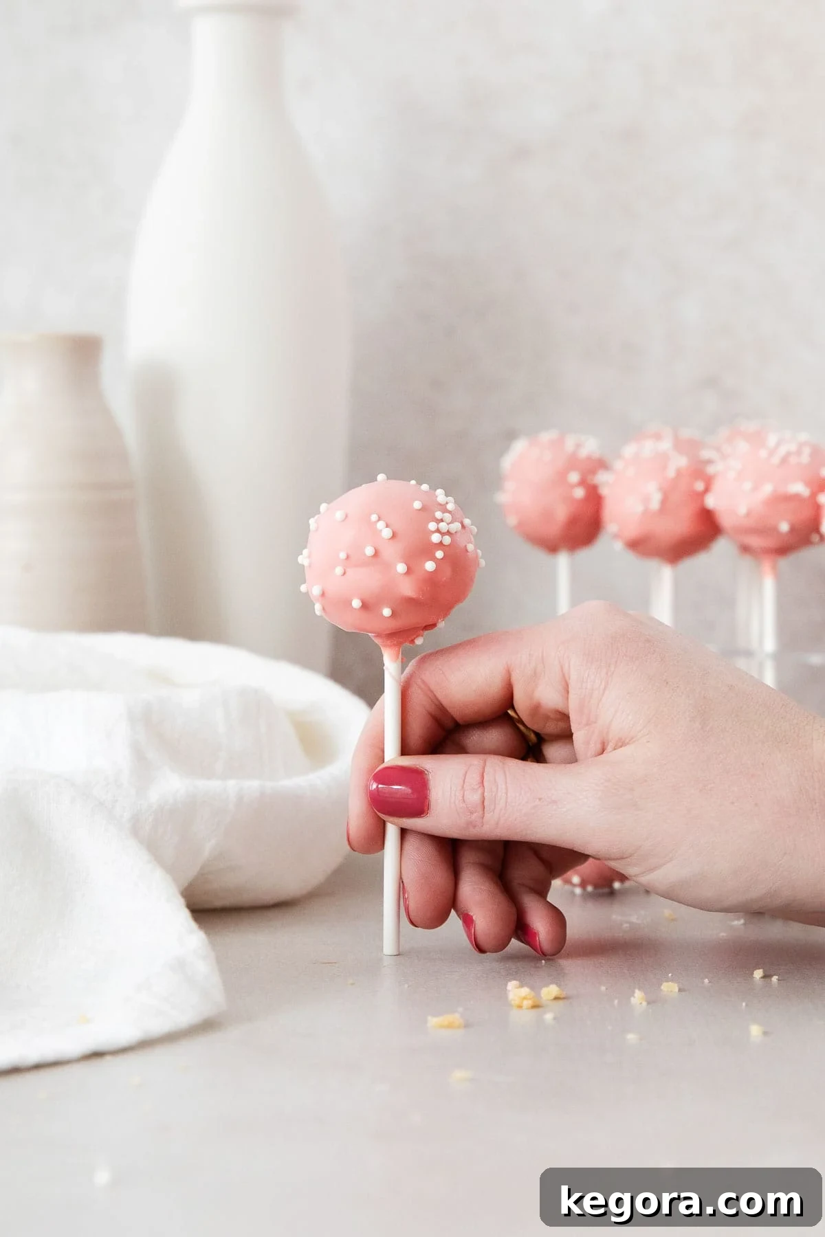 Guilt-Free Cake Pop Delights 6 A hand gracefully holding a beautifully decorated gluten-free cake pop, showcasing its perfect form and vibrant sprinkle coating, ready to be enjoyed.
