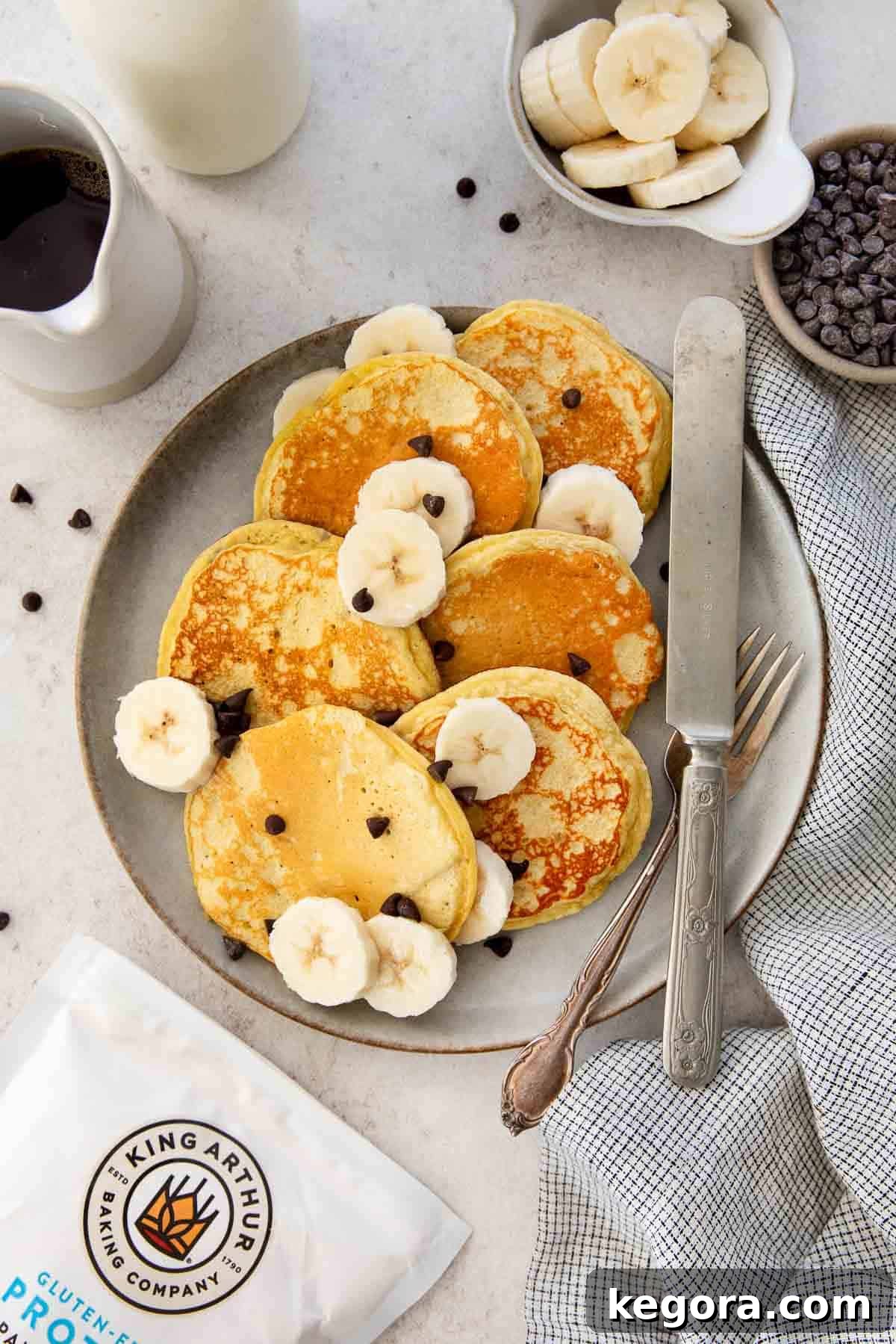 Protein Packed Gluten Free Dairy Free Banana Pancakes 3 Gluten-free banana protein pancakes on a plate with chocolate chips and banana slices.