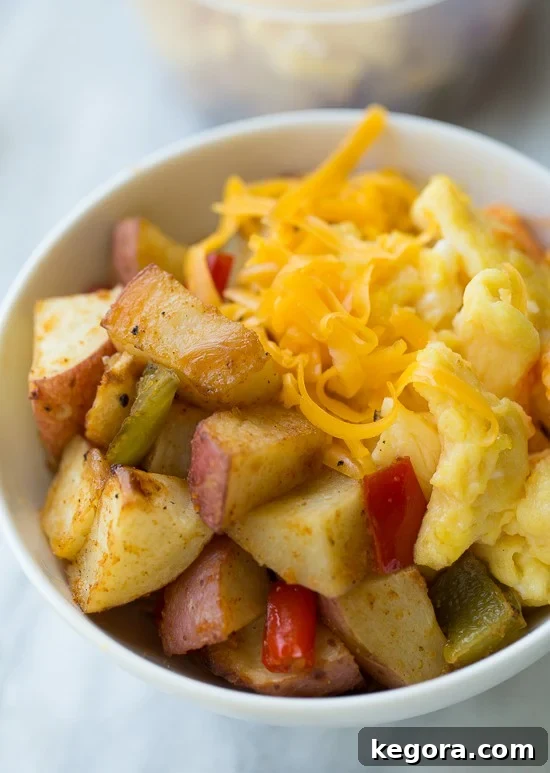 A close-up view of a single make-ahead breakfast potato bowl, showcasing the golden roasted potatoes, fluffy scrambled eggs, and melted cheese, ready to be enjoyed.