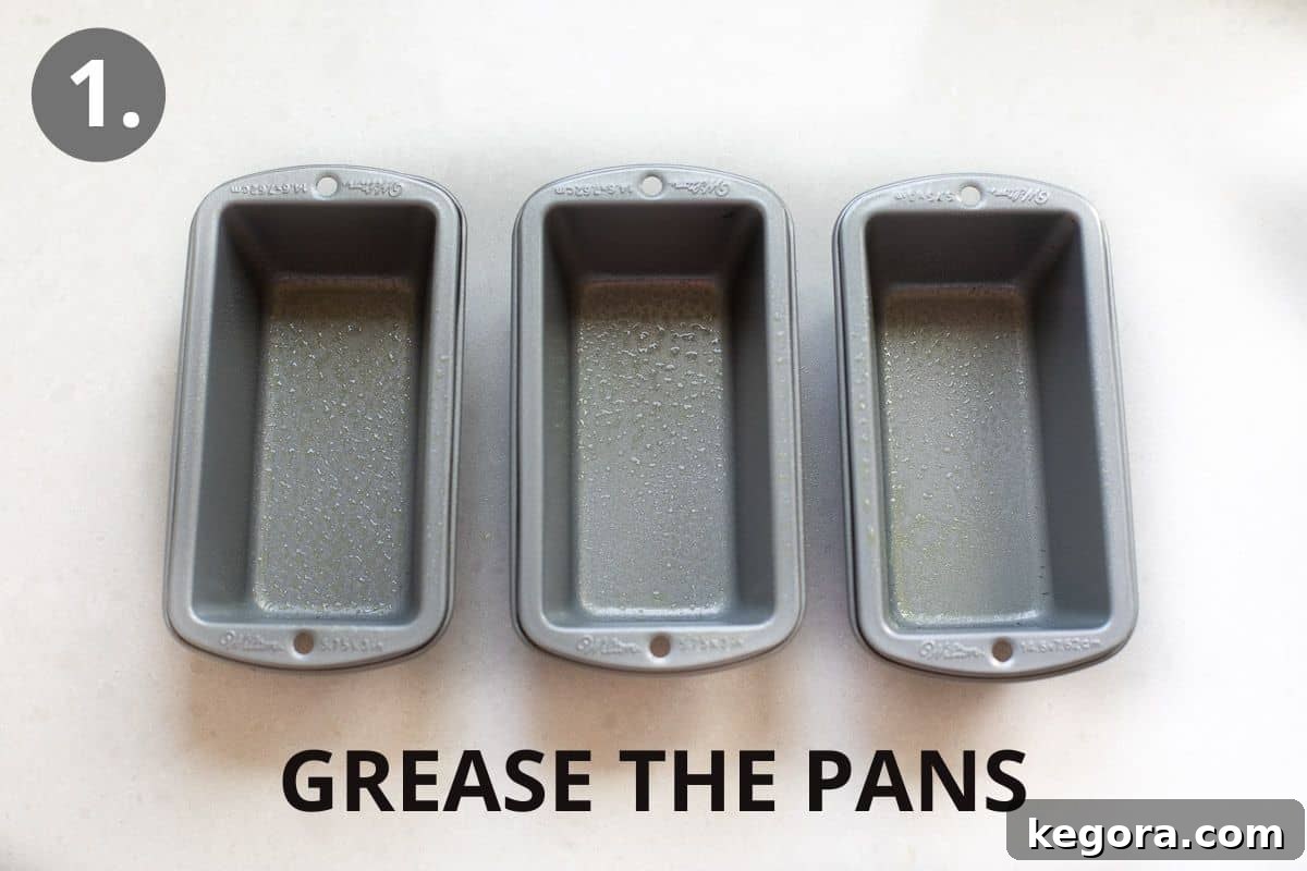 Guilt-Free Zucchini Bread 4 Three greased mini loaf pans neatly lined up on a kitchen countertop, ready for the batter.