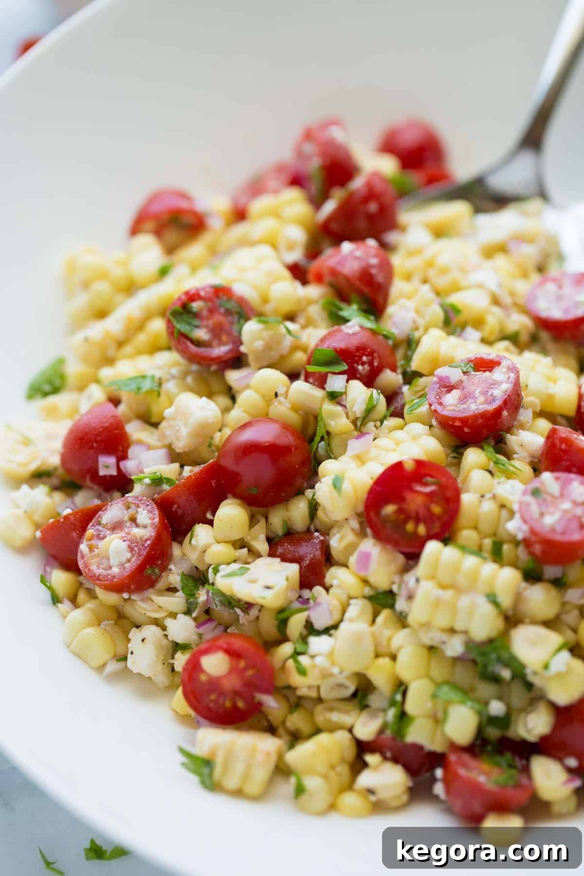 Close-up shot of a refreshing Summer Corn Salad with Feta in a white bowl, garnished with parsley.