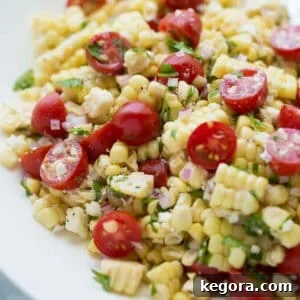 Close-up image of a vibrant corn feta salad in a white bowl topped with fresh parsley.