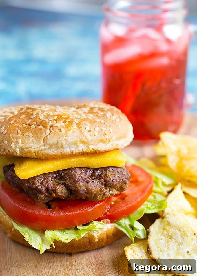 Unlock Juicy Burgers with Your Instant Pot 4 Hamburger on bun with with cheese, tomato slices and lettuce on a wooden board, potato chips.