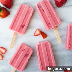 Homemade Strawberry Popsicles Just 4 Ingredients 2 A refreshing strawberry fruit popsicle, showcasing a creamy texture and fresh fruit elements, on a clean marble background.