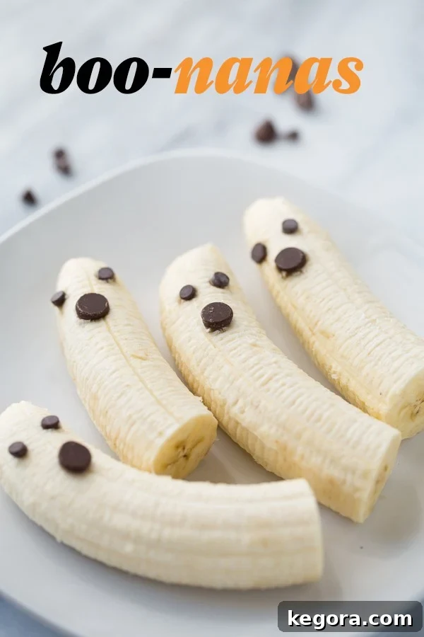 Spooktacularly Healthy Treats 7 Adorable Boo-nanas (banana ghosts) with chocolate chips arranged on a white plate against a marble background.