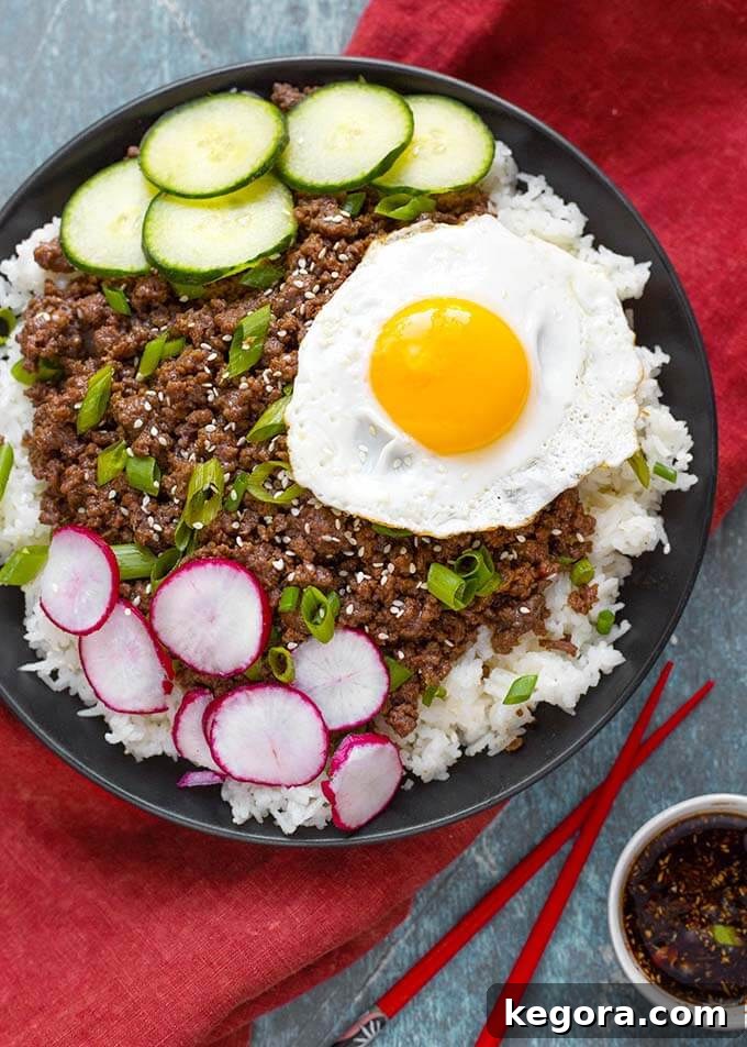 Korean Ground Beef over white rice topped with sliced radish, cucumber, and a cooked egg, garnished with green onions and sesame seeds