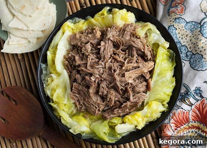 Tender Instant Pot Kalua Pork 6 Top view of Kalua Pork on cooked cabbage on a black plate