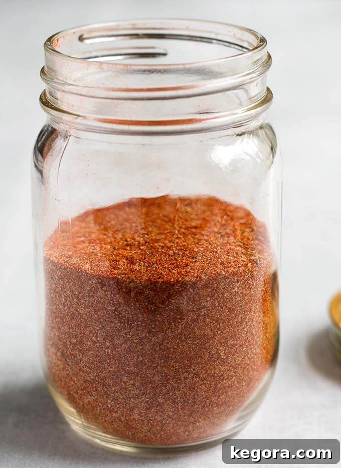 A small glass jar filled with homemade Rotisserie Chicken Spice Rub, sealed with a lid and ready for storage