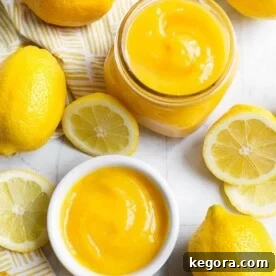 Lemon Curd in a small glass jar and white bowl, all surrounded by cut lemons