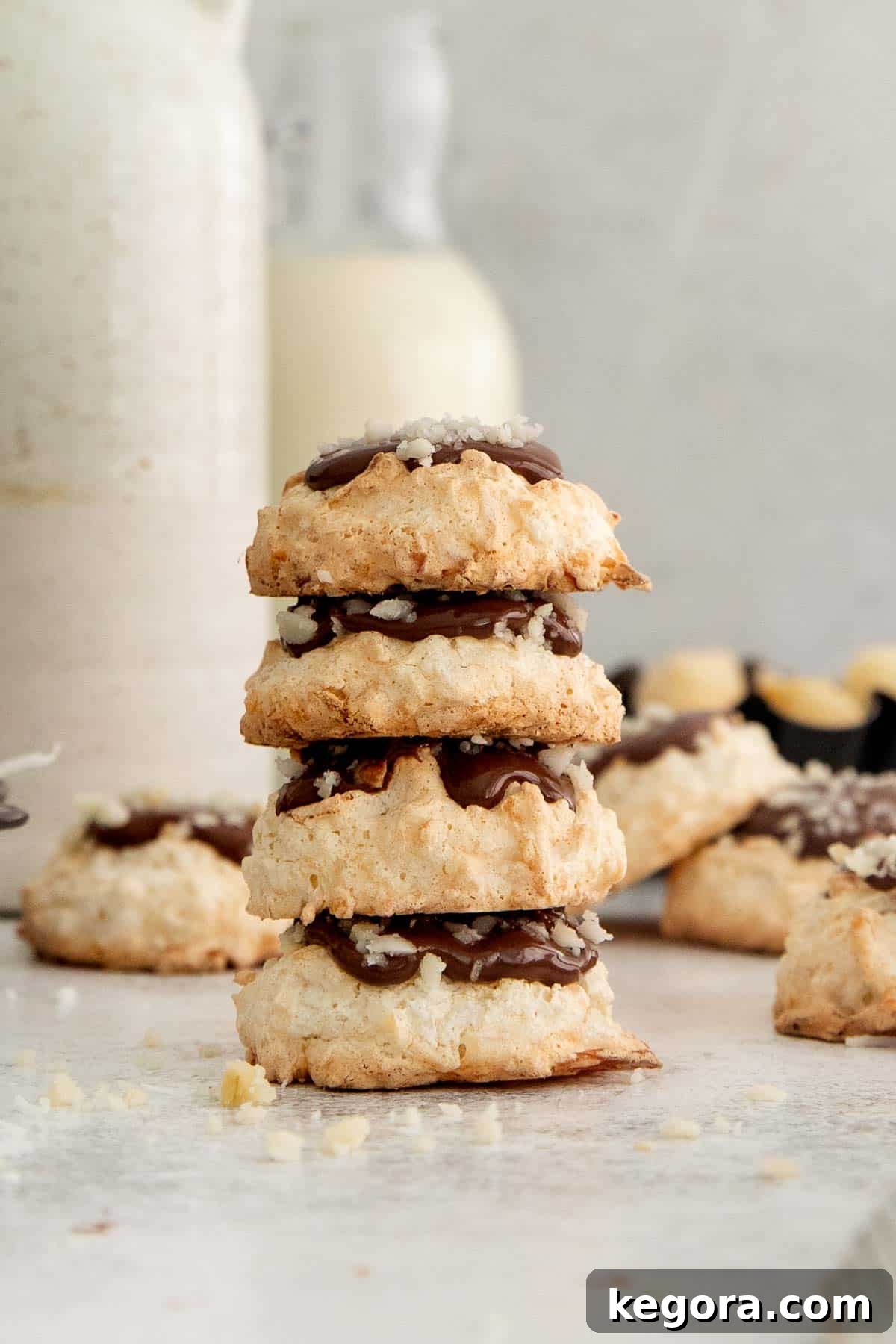 Ethereal Coconut Clouds Gluten Free 3 chocolate coconut cloud cookies stacked in a tower with more in the background.