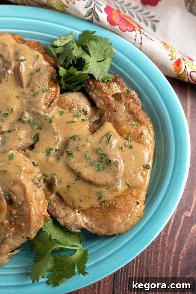 Close-up view of a serving of Instant Pot Pork Chops with Mushroom Gravy on a blue plate, highlighting the rich gravy and tender pork.