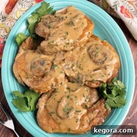 Hearty Instant Pot Pork Chops Smothered in Mushroom Gravy 8 Top view of Instant Pot Pork Chops with Mushroom Gravy on a blue plate, garnished