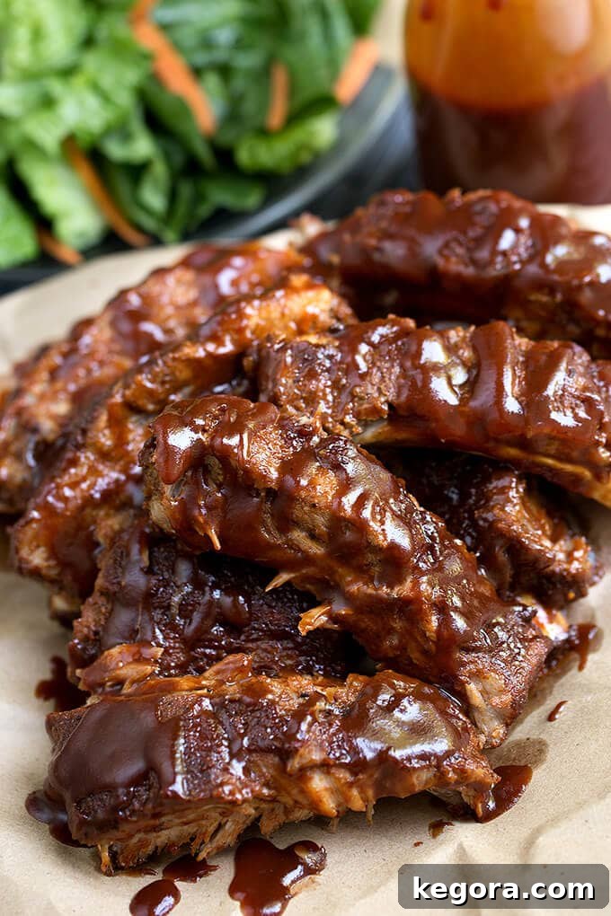 Perfectly cooked Baby Back Ribs glistening with sauce on a beige plate, ready to be enjoyed.