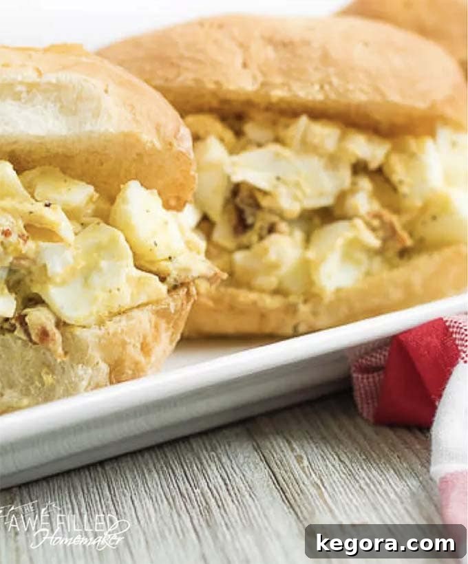 Sweet and spicy egg salad served on a sandwich, presented on a white platter with fresh garnish.